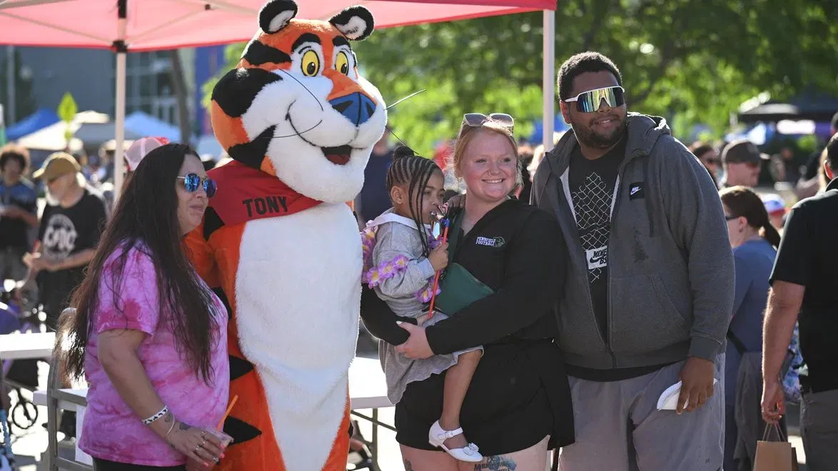 Festival-goers posing with Tony the Tiger under a red tent